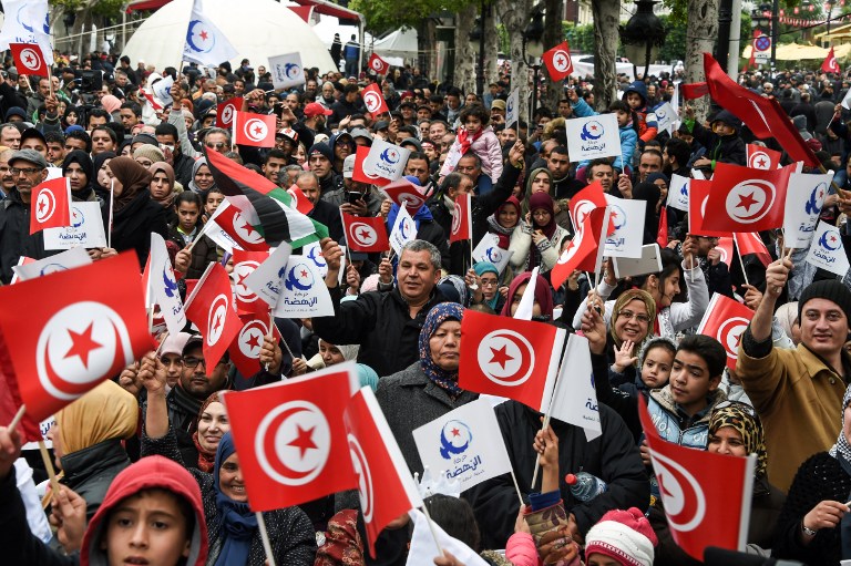 Tunisians wave their national and party flags of the Islamist Ennahdha Party during a rally on January 14, 2017 in the Habib Bourguiba Avenue in the capital Tunis to mark the sixth anniversary of the 2011 revolution. / AFP PHOTO / FETHI BELAID